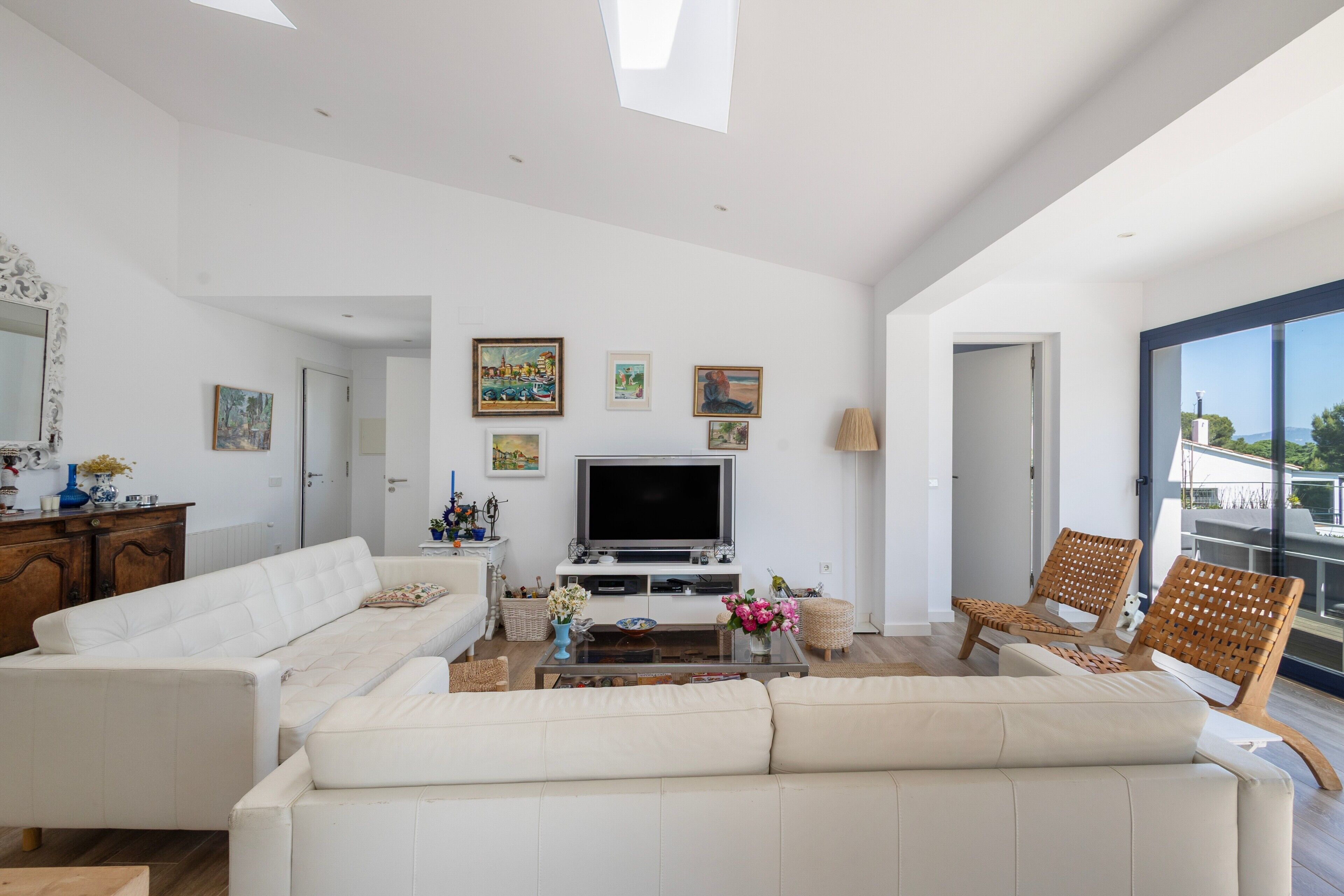 Uma sala de estar moderna com sofá, TV e cadeiras de vime.