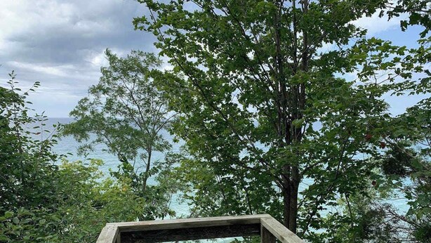 A wooden structure with a view of the ocean and trees. - Lake Michigan Retreat with large patio, gas grill, fire pit, & outdoor hot tub (Fennville)