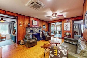 Ein gemütliches Wohnzimmer mit Kamin aus Stein, Ledersofas und Deckenventilator.