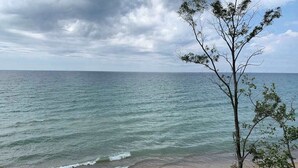 A beach with a view of the ocean and a tree in the foreground. - Lake Michigan Retreat with large patio, gas grill, fire pit, & outdoor hot tub (Fennville)