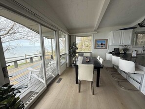 Een moderne keuken met witte kasten, een eettafel met stoelen en uitzicht op het water.