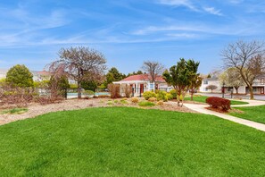 A residential neighborhood with well-maintained lawns, mature trees, and houses with red roofs.