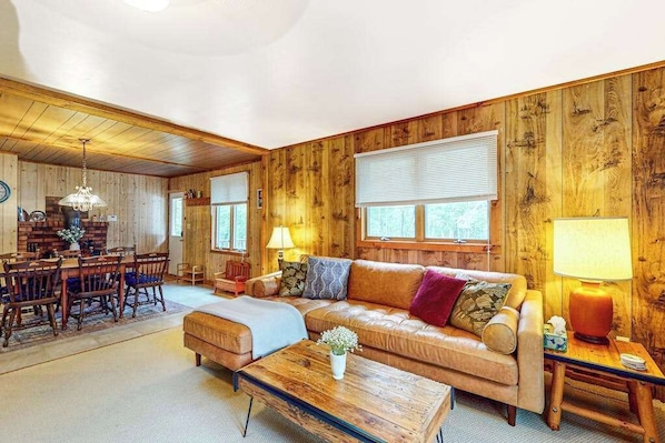 A cozy room with a wooden interior, a sofa, a dining table, and chairs.