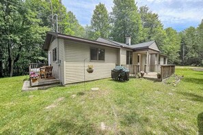 Une cabane de plain-pied avec un porche, un espace barbecue couvert et une petite terrasse.