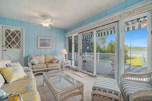 Una habitación con vistas al exterior, una puerta, un sofá, una mesa de vidrio y una silla.