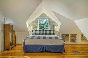 A bedroom with a sloped ceiling, a bed with a blue and white checkered bedspread, and a view of trees through a window. - Terrific riverfront home near the slopes w/ firepit, free WiFi & five-acre lot (Thompsonville)