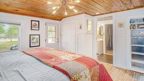 Ein Schlafzimmer mit einem großen Bett, Holzboden und Blick ins Freie.