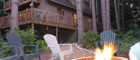 A lodge with a fire pit, outdoor seating, and a large wooden deck.