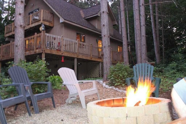 Eine Lodge mit Feuerstelle, Sitzgelegenheiten im Freien und einer großen Holzterrasse.