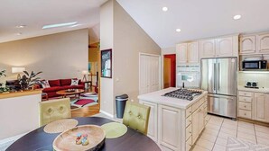 Una cocina moderna con electrodomésticos de acero inoxidable, un comedor con una mesa redonda y una sala de estar con un sofá rojo.