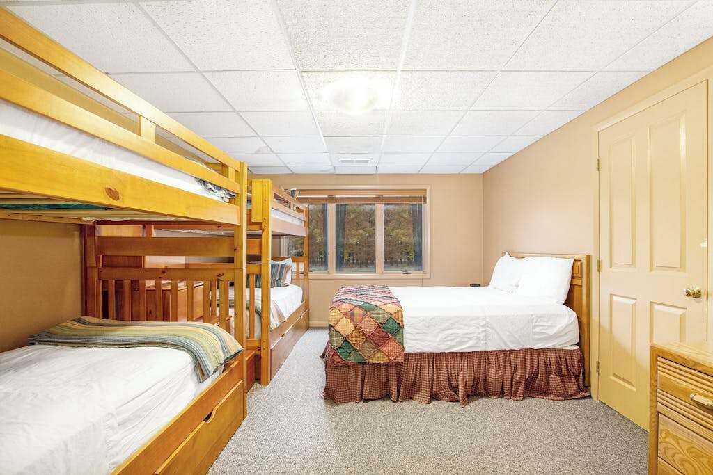 Un dormitorio con literas, una ventana, una puerta y un aparador.