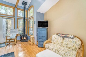 A room with a fireplace, a sofa, a television, and large windows.
