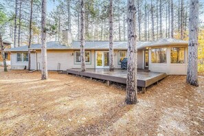 A cabin with a deck, surrounded by trees.