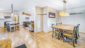 A modern kitchen with a dining area, wooden flooring, and a large table with chairs. - Stunning home w/ golf course views plus private deck near resort amenities (Thompsonville)
