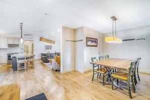 Una cocina moderna con comedor, suelo de madera y una mesa grande con sillas.