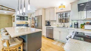 A modern kitchen with a central island, stainless steel appliances, and a view of the outdoors. - Stunning home w/ golf course views plus private deck near resort amenities (Thompsonville)