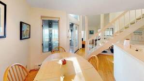 Een eethoek met een tafel, stoelen en een trap naar een ander niveau.