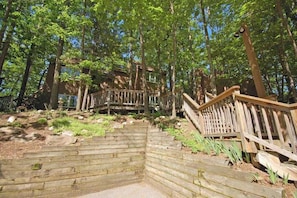 Eine Holztreppe führt zu einem Haus, das von Bäumen umgeben ist.