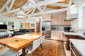 Eine moderne Küche mit Holzbalken, einem Essbereich und einem Wohnraum mit Sofa und Fernseher.
