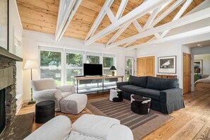 Ein geräumiges Wohnzimmer mit Kamin, Fernseher und großem Fenster.