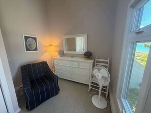 A room with a bed, a dresser, a mirror, a lamp, and a window. - Beautiful beachfront townhouse with deck, water views, community firepit (Glen Arbor)