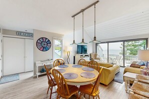 Ein modernes Wohnzimmer mit einem runden Esstisch, Holzstühlen, einer Couch und einem großen Fenster mit Blick.