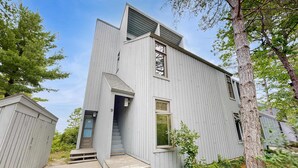 Un bâtiment moderne à deux étages, doté d’une façade en bois, d’une entrée avec des marches et d’un numéro « 9 » bien visible sur la porte.