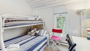 Une chambre de dortoir avec des lits superposés, un bureau, une chaise et une fenêtre avec des stores.