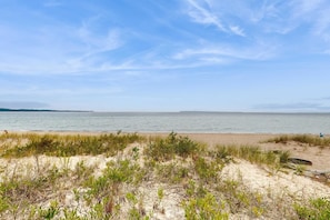 A beach with sand dunes and sparse vegetation. - Beautiful beachfront townhouse with deck, water views, community firepit (Glen Arbor)