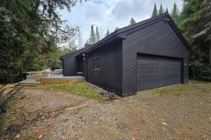 A modern black building with a garage, surrounded by trees.