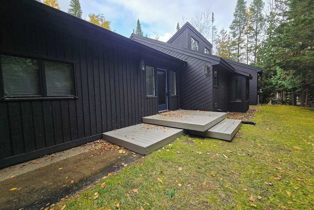 A modern building with a dark exterior, a front door, and a small porch area.