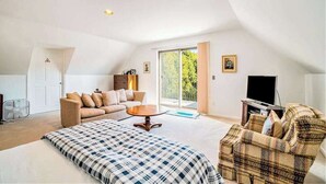 A spacious living room with a large bed, a sofa, a coffee table, and a television.