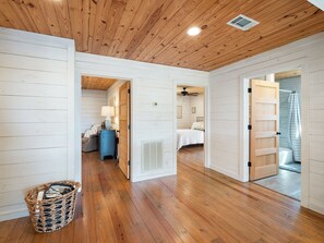 A room with wooden flooring, a bed, a blue cabinet, and a wicker basket.