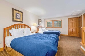 A hotel room with two beds, a nightstand, a lamp, a framed picture, and a door. - Exquisite dog-friendly condo with pool, tennis, hot tub, skiing, & central AC (Boyne Falls)