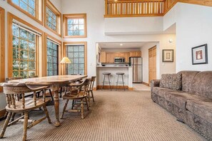 A spacious dining area with a wooden table and chairs, a kitchen with modern appliances, and a cozy living area with a sofa.