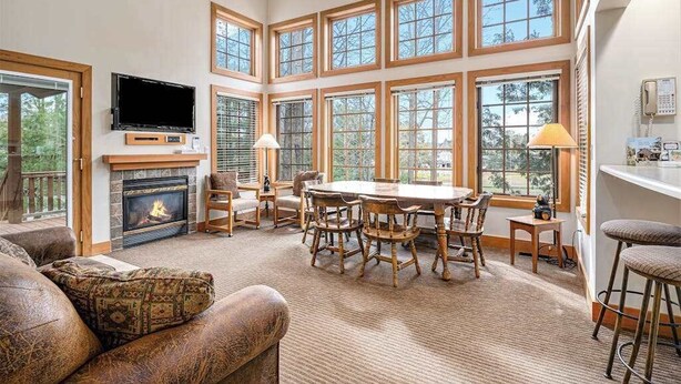 Un salón amplio con chimenea, una gran mesa de comedor y varias ventanas.