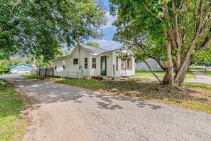 A small, single-story house with a front porch, a garage, and a tree in front.