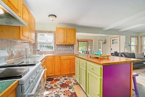 Una cocina con armarios de madera, una estufa y una alfombra colorida.