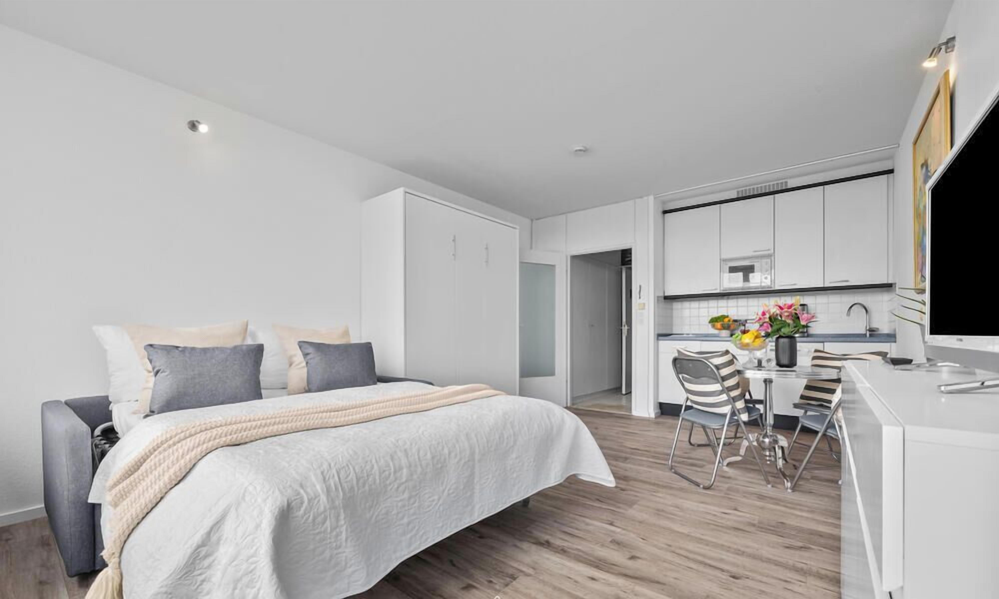 A modern bedroom with a bed, bedside tables, and a desk with a chair.
