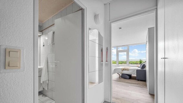 A modern bedroom with a large window, a bed, and a view of the outdoors. - Cozy Holiday Apartment with Limited Sea View near the Beach in Wendtorf (Wendtorf)