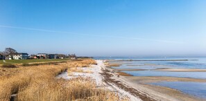 A coastal landscape with a sandy beach, grassy dunes, and a clear blue sky. - Cozy Holiday Apartment with Limited Sea View near the Beach in Wendtorf (Wendtorf)
