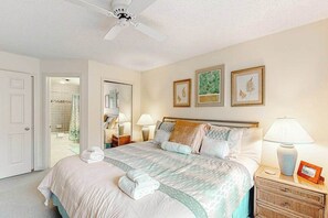 A hotel room with a bed, bedside lamps, a nightstand, and a ceiling fan. - Lovely Lake Michigan beachfront condo with deck, washer/dryer, fireplace, views (Glen Arbor)