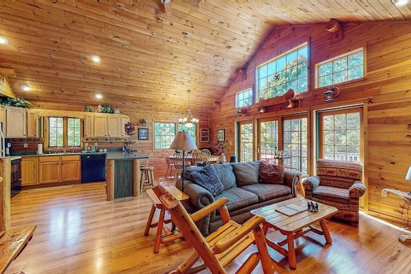 A log cabin interior with a kitchen, dining area, and living room.