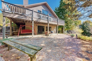 A house with a covered porch, a wooden bench, and a bird on the ground.
