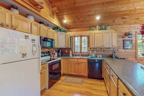 A kitchen with wooden cabinets, a refrigerator, a microwave, an oven, and a dishwasher.