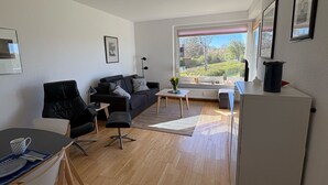 Een moderne woonkamer met een bank, een eettafel en een keukenhoek.