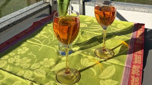 Een tafel met twee glazen amberkleurige vloeistof, een gele tulp en een tafelkleed met een groen patroon.