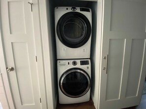 A laundry room with two stacked washing machines. - River-view condo with fireplace, deck, washer/dryer, and community firepit (Glen Arbor)