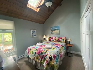 Ein Schlafzimmer mit einem Bett, zwei Nachttischen, einem Deckenventilator und einem Fenster.