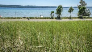 A grassy area with a body of water and trees in the background.